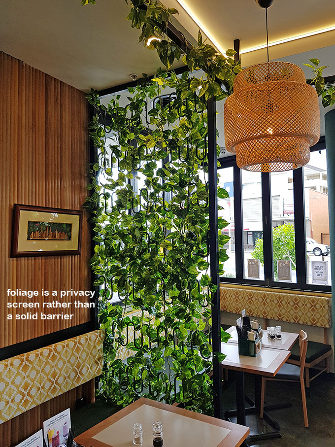 Cafe uses artificial green-vines for privacy screens & pergolas